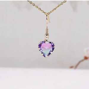 Macro shot of gold-plated earring featuring a heart-shaped purple and blue gradient crystal