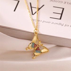 Macro shot of gold butterfly pendant with red, blue and white crystals on silk