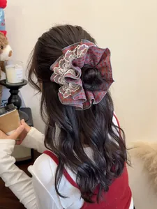 Close-up of red plaid scrunchie with white lace trim worn by a model in a cozy setting