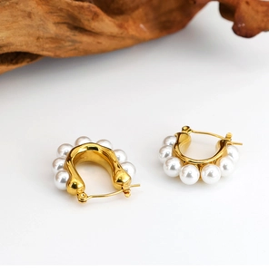 Detailed view of U-shaped gold earrings with white pearls and horseshoe geometric lines