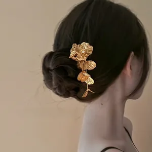 Détail d'épingle à cheveux fleur dorée avec pompons et cristaux sur chignon foncé