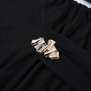 Close-up of black mesh dress featuring a luxury gold metal buckle detail on soft fabric