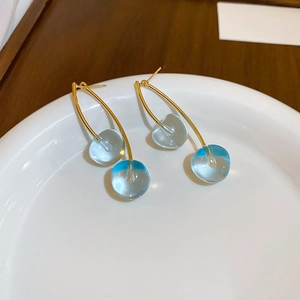 Macro shot of cherry earrings with blue gradient glass beads on white dish detail