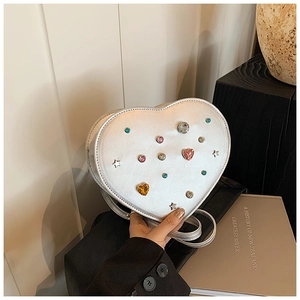 Detail of silver heart-shaped crossbody bag with colorful rhinestones and studs