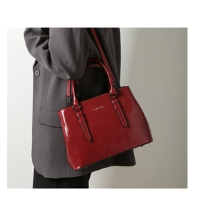 Detailed view of red glossy leather tote bag with handle and shoulder strap details