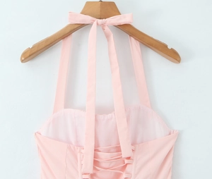 Detailed back view of pink halter dress featuring elegant lace-up cross ties and bow