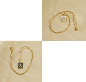 Detail view of square gold titanium steel pendants with white and dark shell inlay