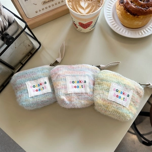 Close-up of three colorful knit plush makeup pouches on a cozy cafe table setting