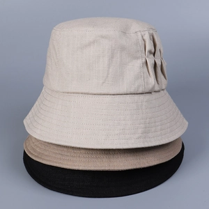 Detailed texture of folded linen sun hats in beige, khaki, and black colors