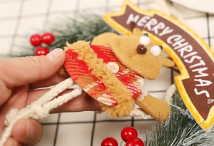Detail der Weihnachts-Rentierpuppe mit rotem Karomuster und Merry Christmas Holzschild