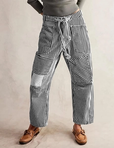 Detail of loose-fit striped trousers with drawstring waist and large side pockets