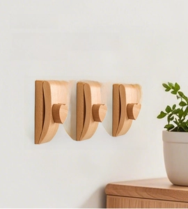 Detail of three wooden quilt hangers with heart motif on white wall with plant