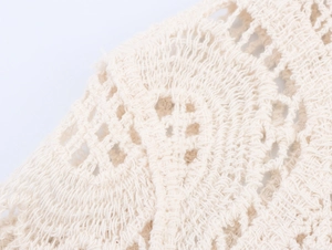 Close-up of beige crochet knit fabric featuring intricate openwork geometric patterns