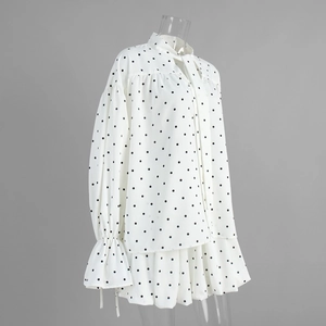 Detailed view of the polka dot blouse with bow-tie collar and bell sleeve ruffled cuffs