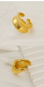Detailed view of wide gold teardrop ring on ceramic and fabric displaying metallic shine