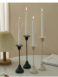 Close-up of matte black and cream metal candle holders with burning spiral candles