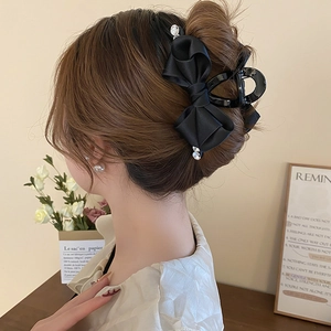 Detailed view of an elegant black satin bow hair claw with rhinestones for updo hairstyles