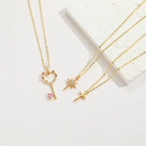 Detailed close-up of 14K gold plated heart key, starburst, and cross pendant necklaces