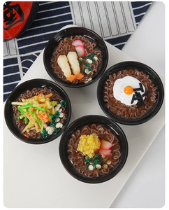 Top view of four miniature Japanese ramen bowls with realistic food details and toppings