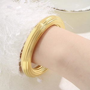Détail du bracelet jonc en acier inoxydable plaqué or 18k avec texture à rayures verticales