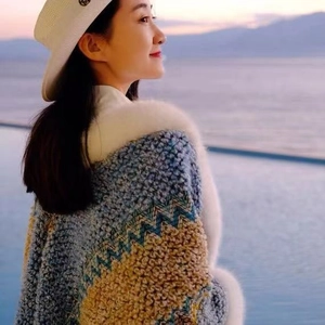 Ethnic knit poncho with faux rabbit fur collar and colorful woven texture at dusk