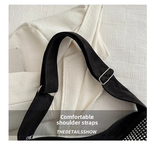 Detail of black suede shoulder strap with silver adjustable buckle and metal rivets