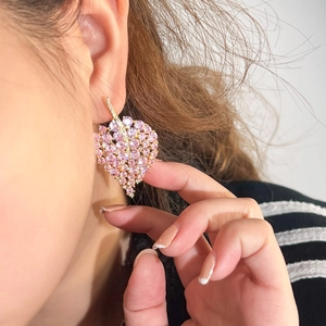 Elegant gold leaf earrings with pink zircon micro-paving on a female ear