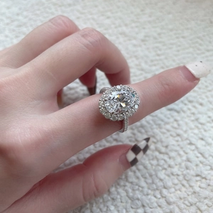 Macro view of an elegant S925 sterling silver halo ring with oval-cut stone on finger