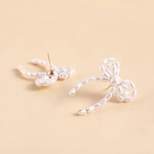 Detail of handmade bow-shaped earrings featuring lustrous faux pearls and gold studs