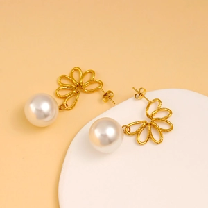 French vintage asymmetric gold flower earrings with large pearls on a beige display