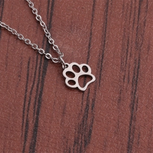 Polished stainless steel dog paw print pendant necklace on a brown leather texture