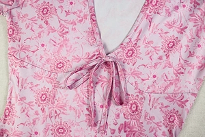 Détail d'une robe fleurie rose avec col en V profond et élégant nœud papillon
