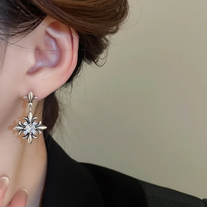 Close-up of vintage silver fleur-de-lis earrings with zircon stones worn by a model