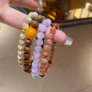 Detail of mixed natural stone and kuka shell beaded bracelets with gold metal accents