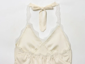 Detail of cream satin halter top featuring deep V-neck and delicate lace trim accents