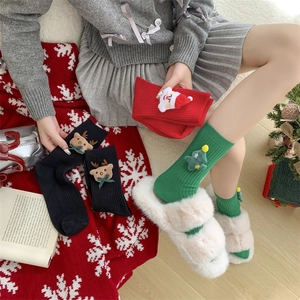 Detail of Christmas crew socks with 3D Santa and Reindeer dolls worn with plush slippers