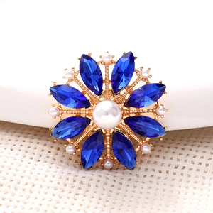 Macro detail of a zinc alloy floral charm with blue navette crystals and large center pearl