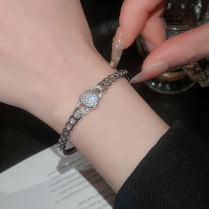 Détail du bracelet chaîne cubaine argenté avec pendentif ovale pavé porté au poignet