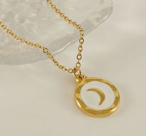 Macro detail of 18K gold stainless steel necklace featuring a white moon pendant charm