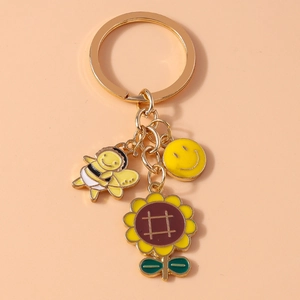 Detail view of sunflower, honeybee, and smiley face enamel charms on a golden keychain