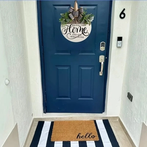 Close-up of coconut fiber hello doormat and round wooden welcome sign on a blue front door