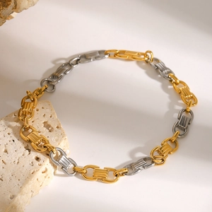 Bracelet chaîne bicolore en acier inoxydable or et argent sur un support en pierre