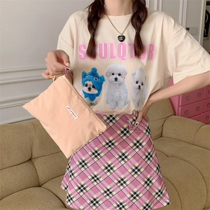 Detail of pink fabric clutch bag with SORAKA label held by a model in casual home setting
