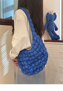 Close-up of blue puffy cloud bag with pleated texture worn as a shoulder bag