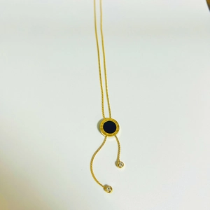 Detail of gold titanium necklace with Roman numerals pendant and zircon tassels