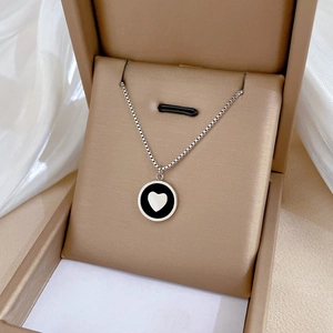 Macro shot of silver titanium heart pendant necklace resting in a beige jewelry gift box
