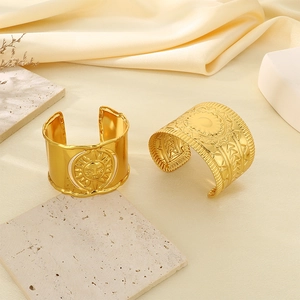 Detail of gold-plated wide open bangles with sun relief and geometric textured patterns