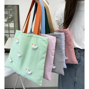Detail of colorful seersucker tote bags with 3D duck dolls and thick woven straps