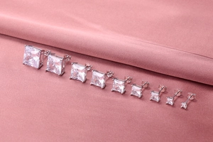 Detailed set of nine S925 silver square zircon stud earrings on pink silk fabric