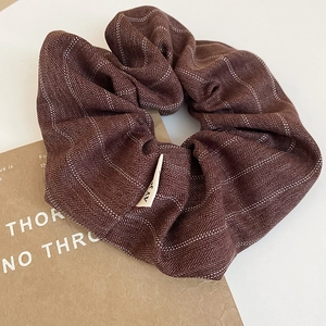 Macro detail of retro striped scrunchie showing coffee brown fabric and woven texture